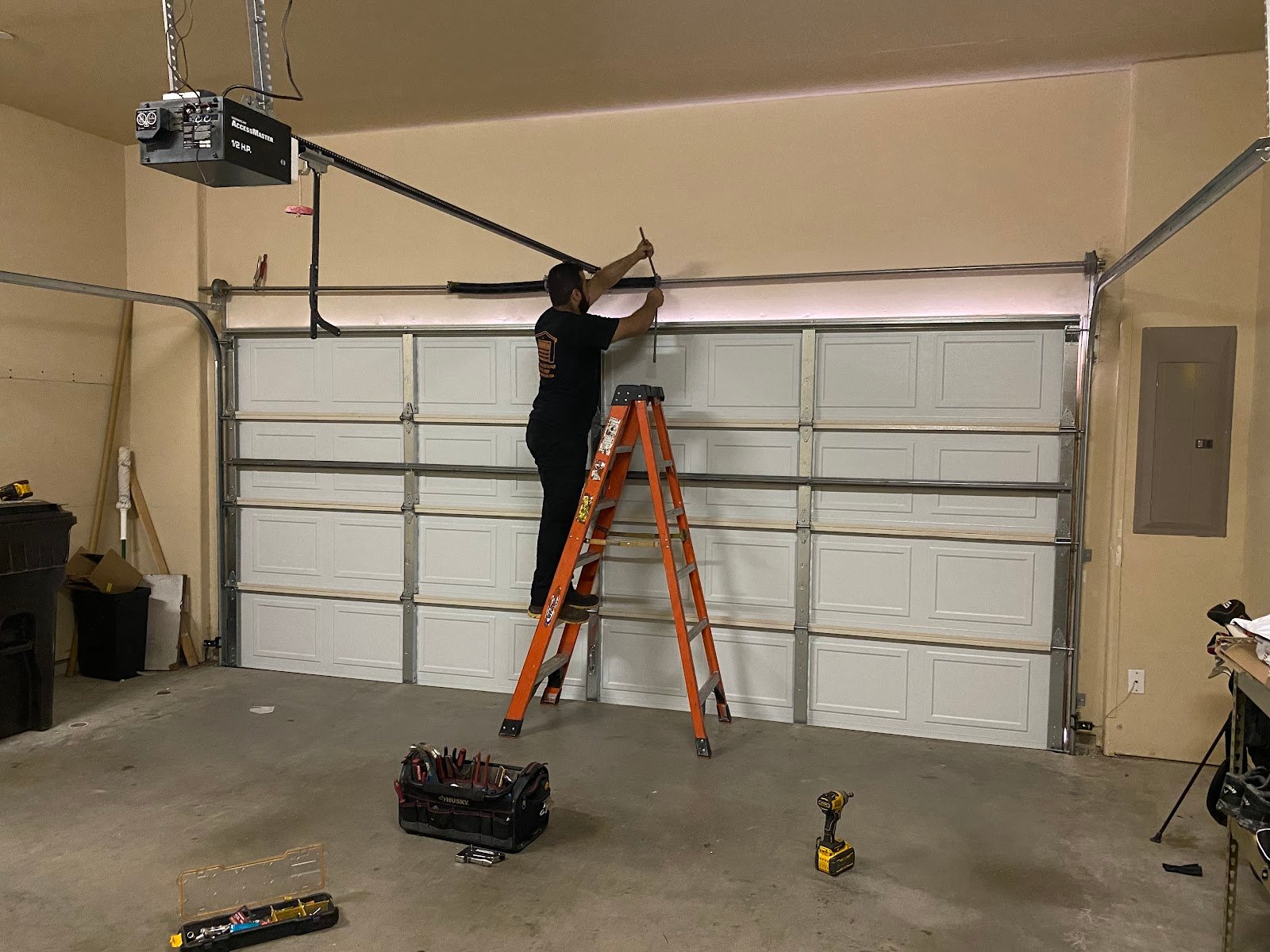 Technician servicing a residential garage door from inside the garage